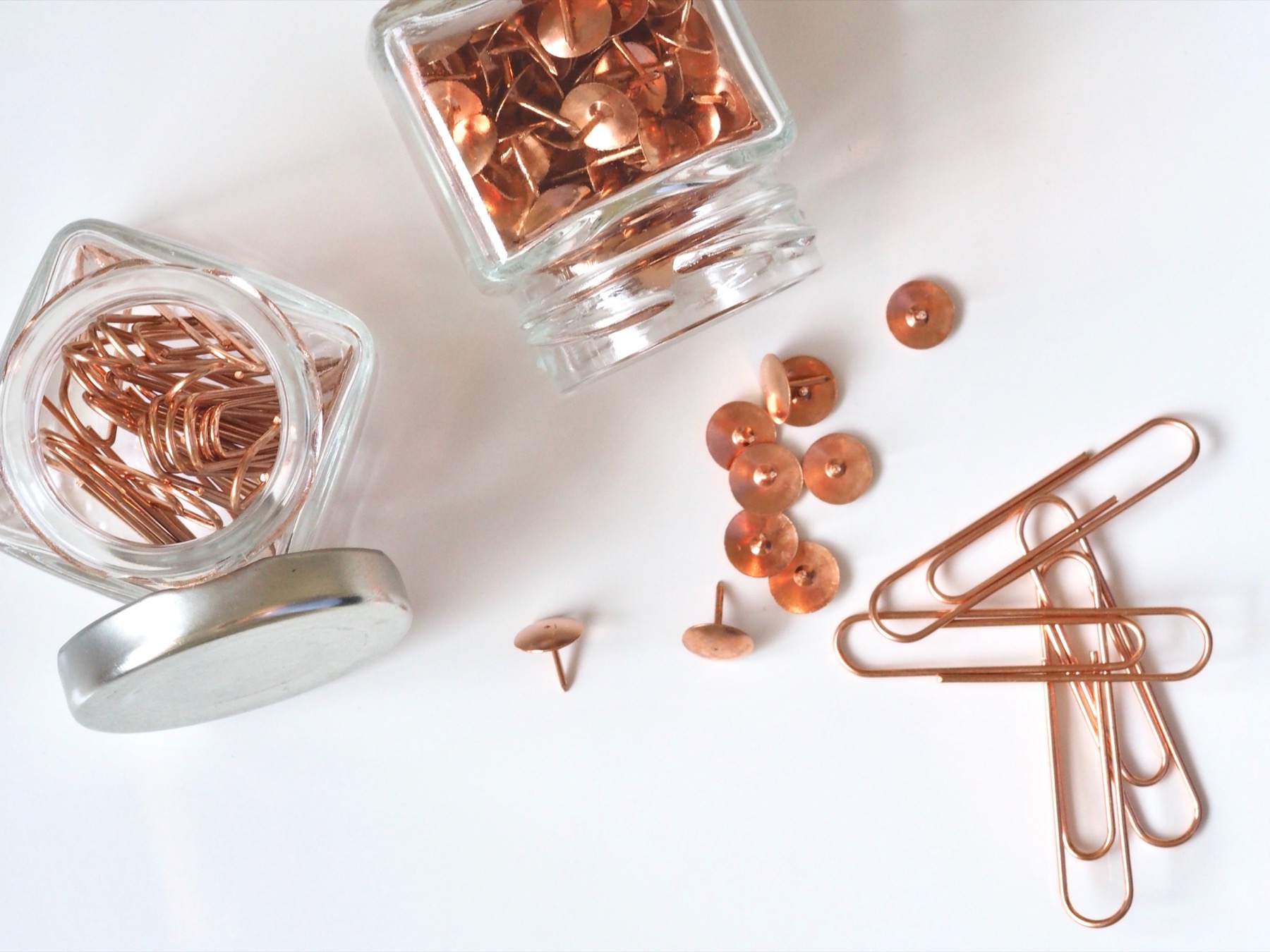 Koperen paperclips, punaises en een glas op een helder bureau